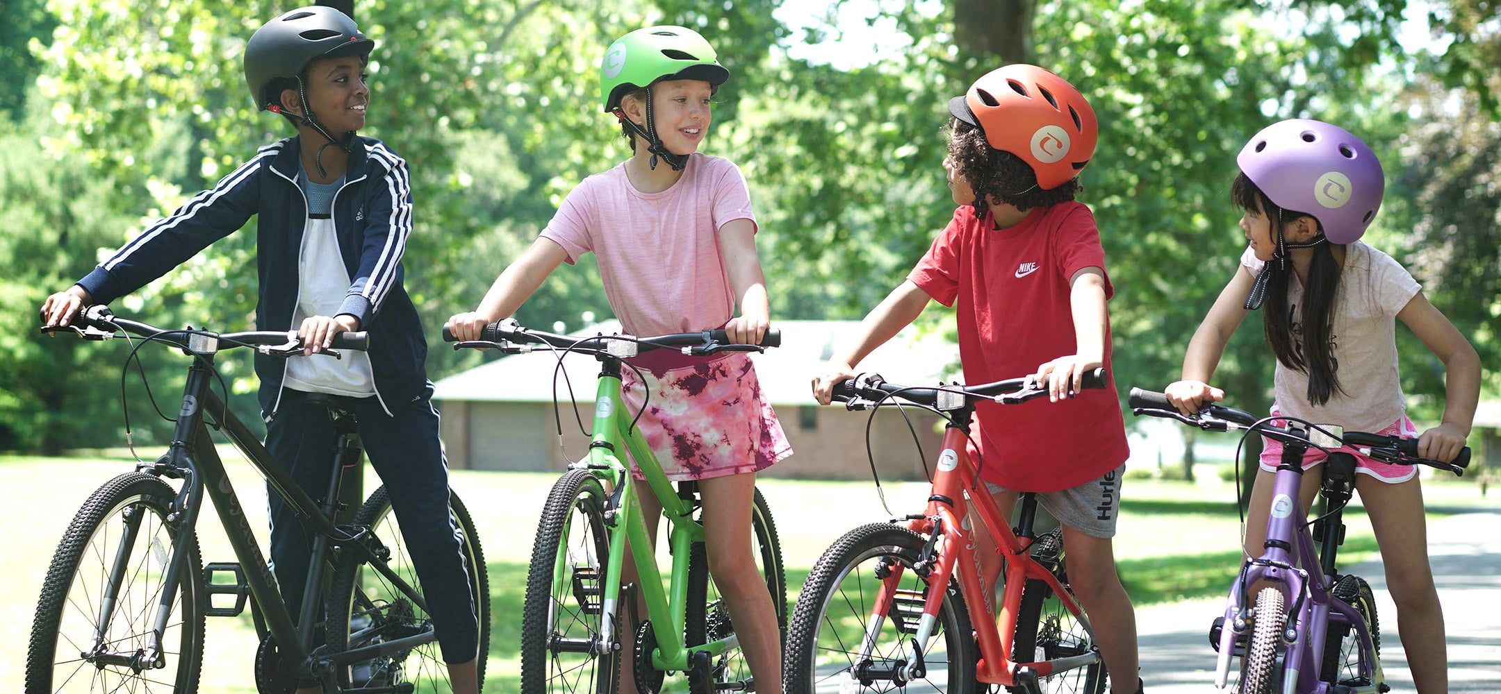 A lineup of kids standing side by side with their 12" to 26" CYCLEKids Bikes and matching helmets