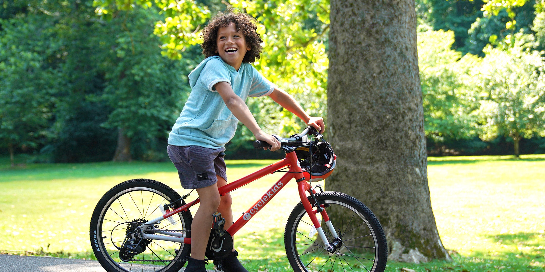A little boy smiling with his 20" Orange CYCLEKids Bike