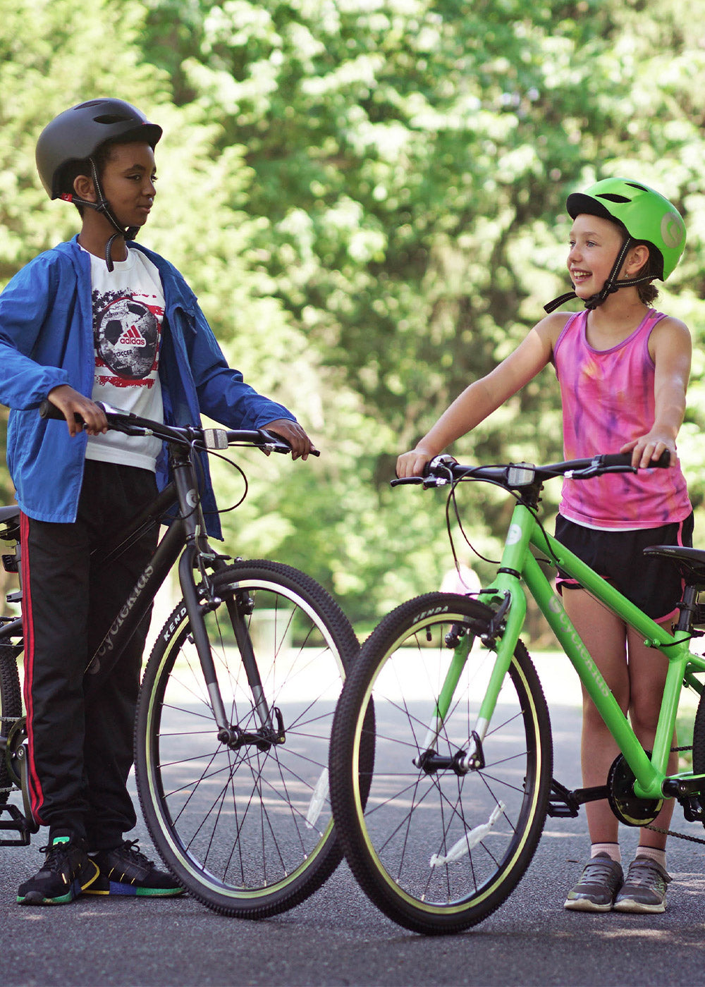 A boy and a girl standing with a 24" and 26" CYCLEKids bikes
