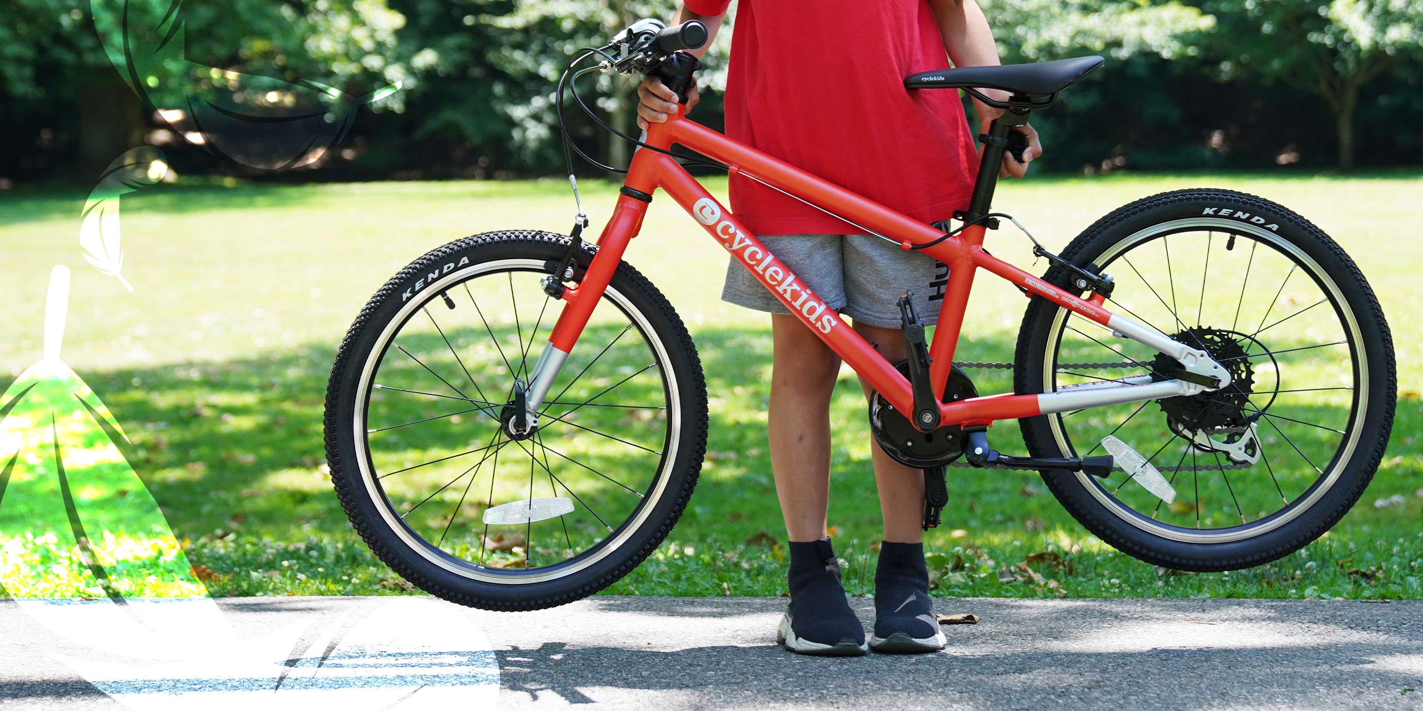A little boy effortlessly lifting a lightweight 20" CYCLEKids bike in orange off the ground